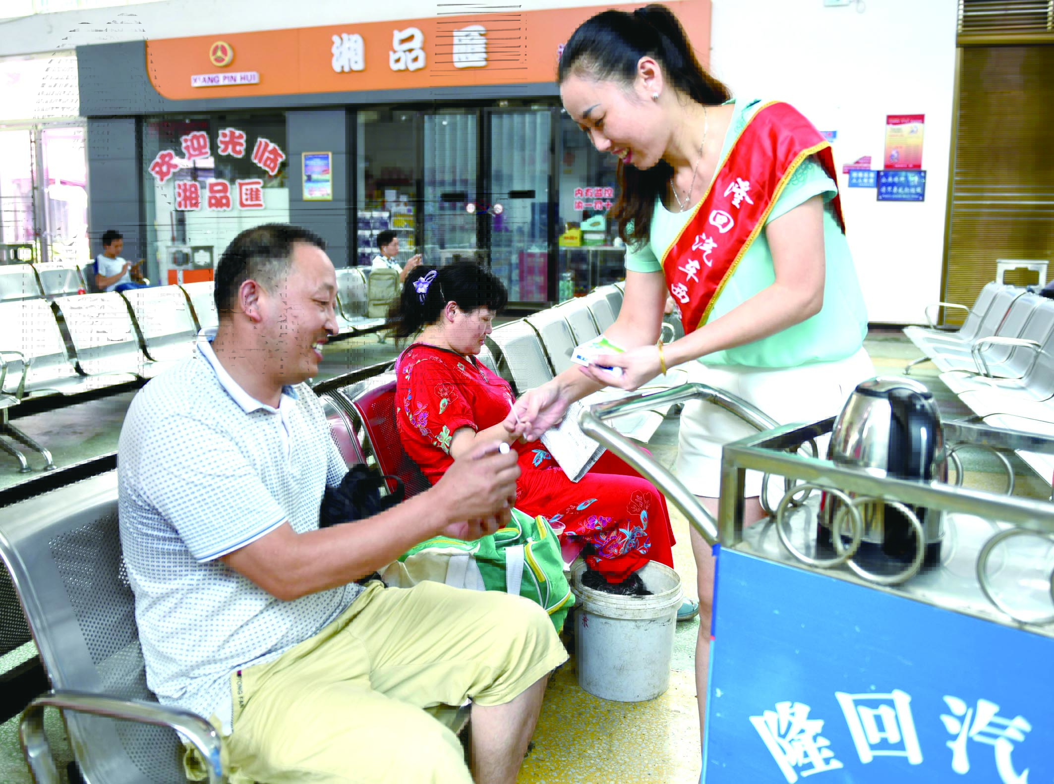隆回分公司汽車西站工作人員正在為旅客免費(fèi)贈(zèng)送藿香正氣水。